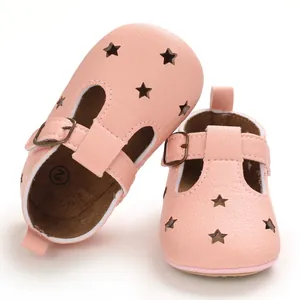 Close-up of pink baby shoes with star cutouts and bronze buckle on white background