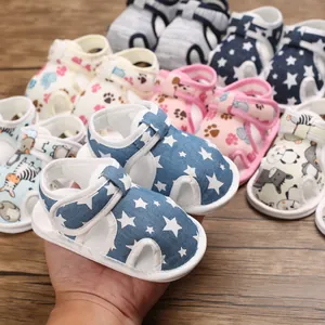 Primer plano de sandalias para bebé con suela blanda y un diseño de estrellas azules.