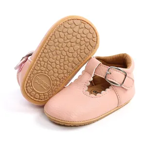 Close-up of pink baby girl princess shoes with scalloped edges and textured rubber sole.