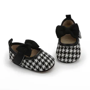 Detail von Baby Mädchen Prinzessinnenschuhen mit Hahnentrittmuster und Schleife