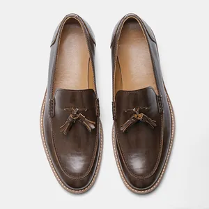 Top view of dark brown leather tassel loafers with a subtle wood grain texture