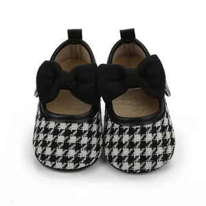 Detailansicht der Baby-Prinzessin-Schuhe mit Hahnentrittmuster und schwarzer Schleife.