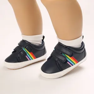 Vue détaillée de chaussures pour bébé bleu marine avec bandes arc-en-ciel.