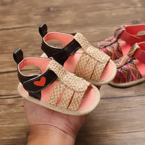 Close-up of soft-sole baby sandals with woven straps and heart detail