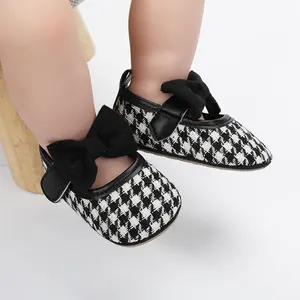 Detailaufnahme von Babyschuhen für Mädchen mit Hahnentrittmuster und großer Schleife.
