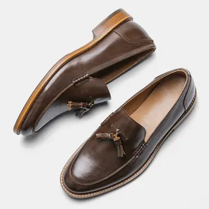 Close-up detail of brown leather loafers for men featuring elegant tassels and wood-grain heels