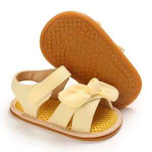 Detalle de sandalias de algodón amarillo para bebé con lazo y suela de goma blanda con estrellas