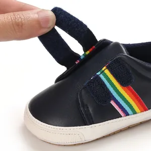 Gros plan sur chaussure de bébé bleu marine avec rayures arc-en-ciel et velcro