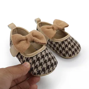 Nahaufnahme von Baby-Prinzessin-Schuhen mit Hahnentritt-Muster und brauner Schleife
