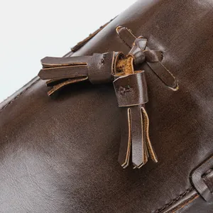 Macro detail of the elegant brown leather tassel on a men's business loafer shoe