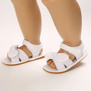 Detalle de sandalias blancas para bebé con lazo dulce y suela blanda para verano