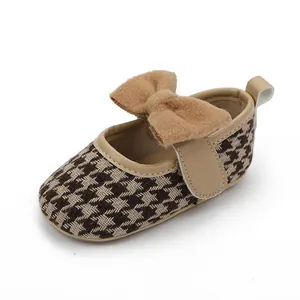 Nahaufnahme brauner Baby-Prinzessinnenschuhe mit Hahnentrittmuster und Schleife