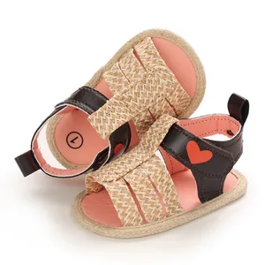 Detail of pink and brown baby sandals with red heart pattern and woven straps