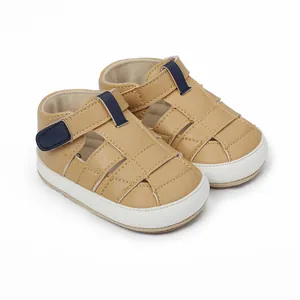 Detailed macro view of tan infant walking sandals with navy blue velcro straps.
