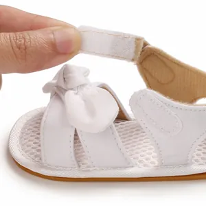 Primer plano de una sandalia blanca de bebé que muestra el cierre de velcro suave