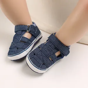 Primo piano di scarpe primi passi in denim blu per neonati con suola in stoffa bianca.