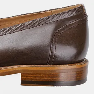 Macro detail of the stacked wood grain heel and brown leather stitching on men's loafers