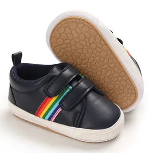 Détail de chaussures de marche pour bébé bleu marine avec rayures arc-en-ciel et semelle souple.