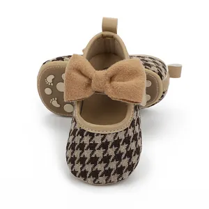 Nahaufnahme von Babyschuhen für Mädchen mit Hahnentrittmuster und großer brauner Schleife