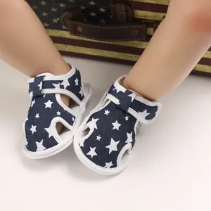 Primer plano de sandalias azul marino para bebé con diseño de estrellas y velcro.