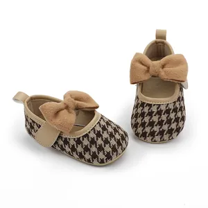 Detail von Baby-Prinzessin-Schuhen mit braunem Hahnentritt-Muster und Schleife