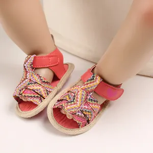 Close-up of red baby girl summer sandals with colorful woven straps and heart detail