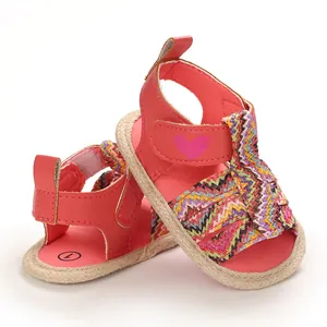 Detailed view of pink baby sandals featuring colorful woven straps and a heart detail