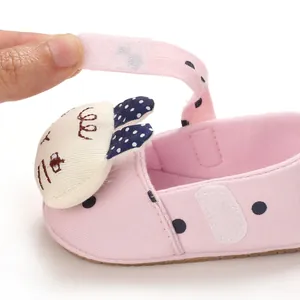 Detailed view of pink polka dot baby walking shoe featuring an adjustable velcro strap
