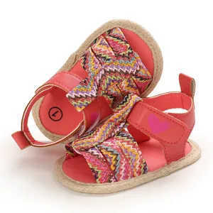 Detailed view of pink baby girl walking shoes featuring a heart and colorful woven strap