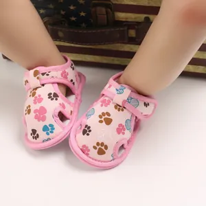 Detalle de sandalias rosas para bebé con suela blanda y divertidos dibujos de patas