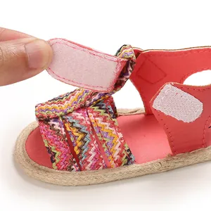 Close-up detail of infant girl summer sandal with adjustable pink velcro and woven strap