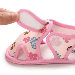 Detalle macro de sandalia rosa para bebé con cierre de velcro y estampado de huellas