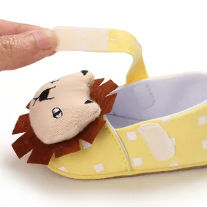 Detail of yellow baby toddler shoe with hook and loop strap and a cute cartoon lion head.