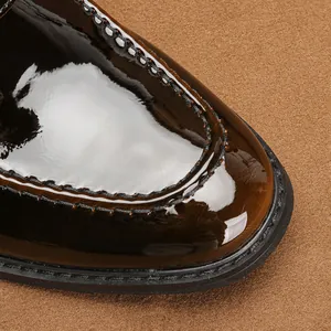 Detailed macro shot of men's glossy patent leather loafers showing exquisite stitching