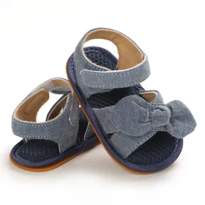 Primer plano de sandalias para bebé hechas de algodón denim azul con un lazo decorativo