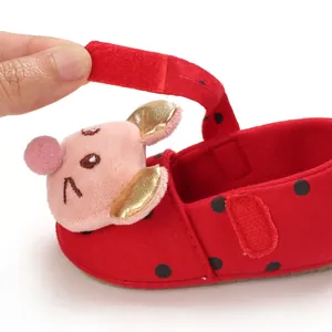 Close-up of red polka dot baby shoe featuring pink pig detail and Velcro strap.