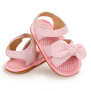 Detalle de sandalias rosas para bebé con lazo decorativo y tejido de malla.