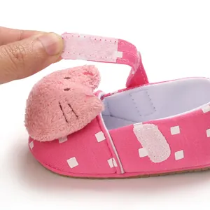 Detailed view of pink baby walking shoe featuring velcro strap and plush cat head decor