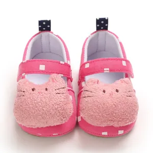Close-up of pink baby walker shoes with cute plush cartoon cat face and velcro strap.