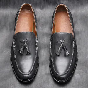 Detail view of black leather loafers featuring textured finish and elegant double tassels.