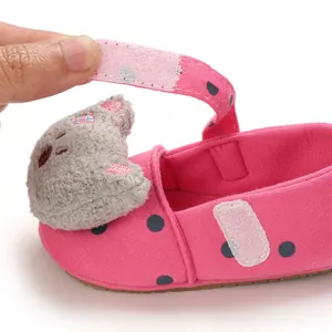 Detailed macro view of pink polka dot baby walking shoe featuring velcro strap and cat