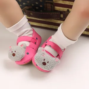 Close-up of pink baby walking shoes with cute plush bear and polka dot patterns