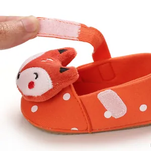 Detail view of adjustable hook-and-loop strap on orange fox soft sole baby shoe