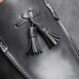 Macro close-up shot of a black leather business loafer featuring elegant tassel detail