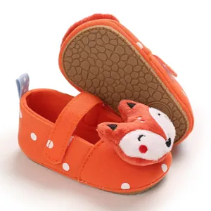 Detail view of orange polka dot baby shoes with plush fox character and soft sole