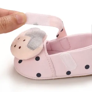 Detail view of the pink polka dot baby shoe with adjustable hook and loop strap