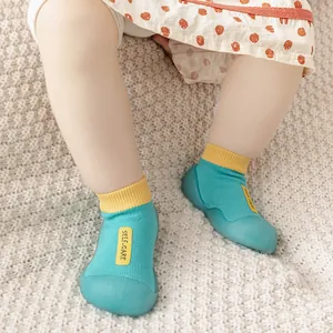 Nahaufnahme eines Babys mit blau-gelben Lauflernschuhen auf einer weichen Decke