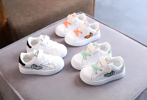 Three pairs of stylish white children's sneakers in black, orange, and green colors.