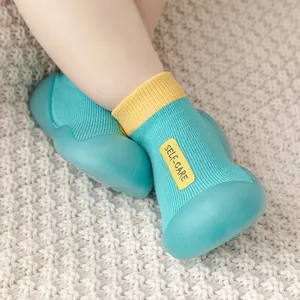 Nahaufnahme von petrolfarbenen und gelben Babysocken-Schuhen mit rutschfesten Gummisohlen
