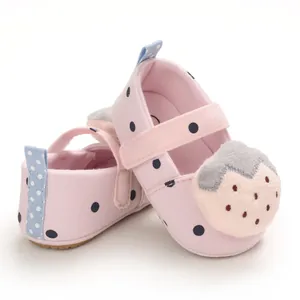 Detailed view of pink baby walker shoes featuring cute plush strawberry and polka dots.